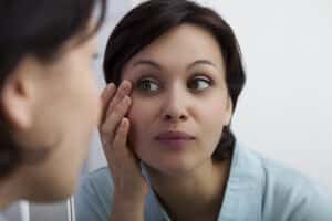 Woman examines her refreshed eyes after cosmetic blepharoplasty.